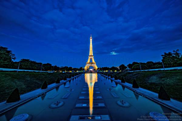Illuminierter Eiffelturm bei Nacht spiegelt sich im Wasser vor dem großen Feuerwerk zum Nationalfeiertag am 14. Juli 2019 in Paris