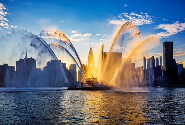 Feuerlöschboot mit Wasserfontänen von der New Yorker Skyline beim Unabhängigkeitstag am 4. Juli / Macy's Fourth of July Fireworks - NYC - Independence Day Celebrations