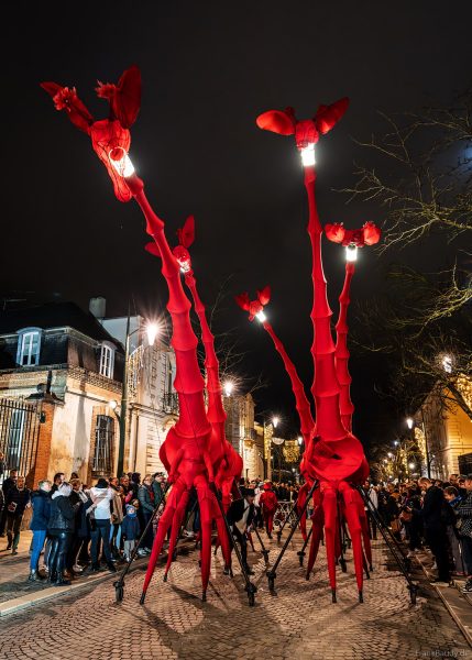 Riesige rote Giraffen von Compagnie Off ziehen durch die Avenue de Champagne bei Habits de Lumière