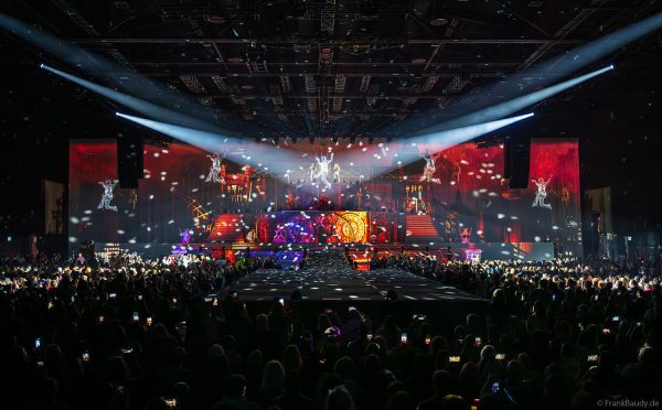 Akrobaten als spiegelnde Lichtgestalten fliegen durch die Halle beim DJ BoBo Konzert – The Great Adventure