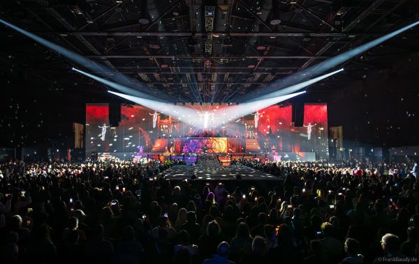 Akrobaten als spiegelnde Lichtgestalten fliegen durch die Halle beim DJ BoBo Konzert – The Great Adventure