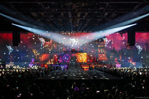 Akrobaten als spiegelnde Lichtgestalten fliegen durch die Halle beim DJ BoBo Konzert – The Great Adventure