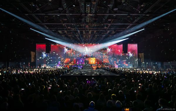 Akrobaten als spiegelnde Lichtgestalten fliegen durch die Halle beim DJ BoBo Konzert – The Great Adventure