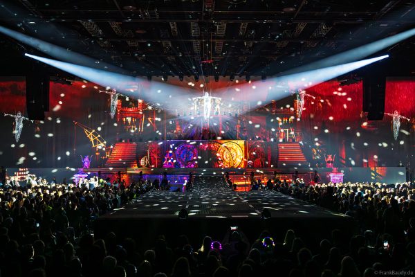 Akrobaten als spiegelnde Lichtgestalten fliegen durch die Halle beim DJ BoBo Konzert – The Great Adventure