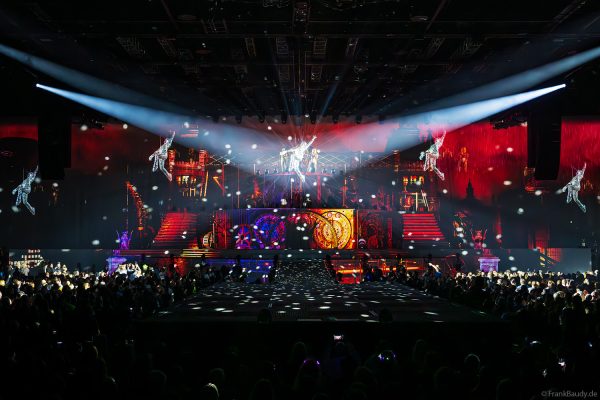 Akrobaten als spiegelnde Lichtgestalten fliegen durch die Halle beim DJ BoBo Konzert – The Great Adventure