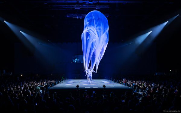 Turner performen mit einem Tuch im Luftstrom eindrucksvoll im Licht auf der Bühne bei DJ BoBo – The Great Adventure