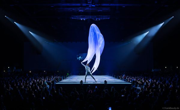 Turner performen mit einem Tuch im Luftstrom eindrucksvoll im Licht auf der Bühne bei DJ BoBo – The Great Adventure