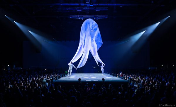 Turner performen mit einem Tuch im Luftstrom eindrucksvoll im Licht auf der Bühne bei DJ BoBo – The Great Adventure