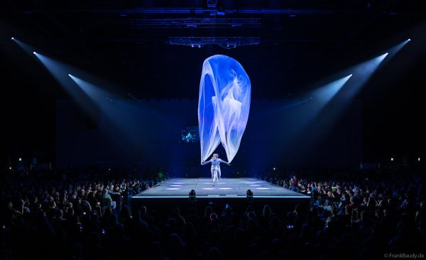 Turner performen mit einem Tuch im Luftstrom eindrucksvoll im Licht auf der Bühne bei DJ BoBo – The Great Adventure