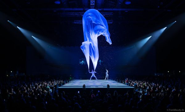 Turner performen mit einem Tuch im Luftstrom eindrucksvoll im Licht auf der Bühne bei DJ BoBo – The Great Adventure