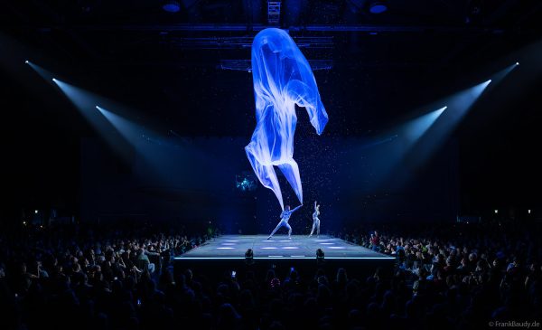 Turner performen mit einem Tuch im Luftstrom eindrucksvoll im Licht auf der Bühne bei DJ BoBo – The Great Adventure