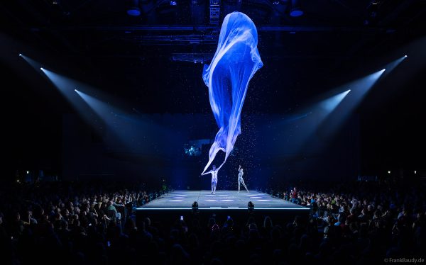 Turner performen mit einem Tuch im Luftstrom eindrucksvoll im Licht auf der Bühne bei DJ BoBo – The Great Adventure