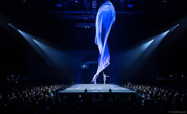 Turner performen mit einem Tuch im Luftstrom eindrucksvoll im Licht auf der Bühne bei DJ BoBo – The Great Adventure