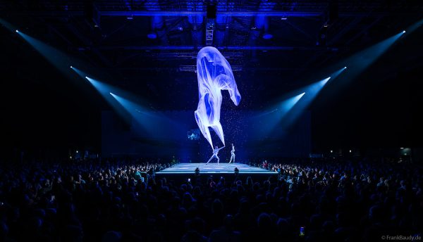 Turner performen mit einem Tuch im Luftstrom eindrucksvoll im Licht auf der Bühne bei DJ BoBo – The Great Adventure