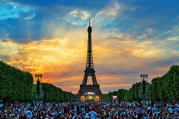 Zehntausende Besucher auf dem Champ-de-Mars warten bei Sonnenuntergang auf das Concert de Paris und das Feuerwerk am Eiffelturm